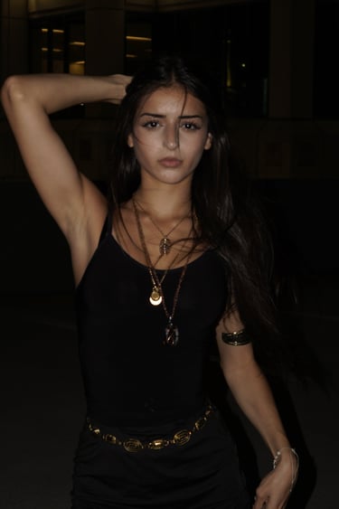 Miami lifestyle portrait of a brunette woman in black tank top and gold necklaces at night by Frank