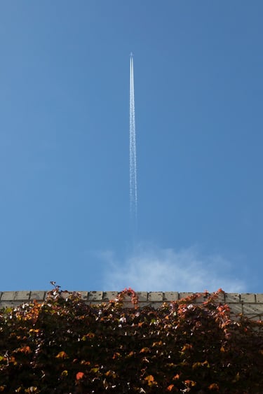 A jet flying above with a white trail behind.