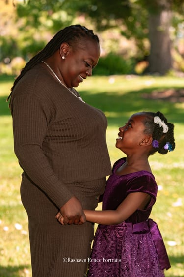 a woman in a purple dress standing next to a young girl in a family Portrait