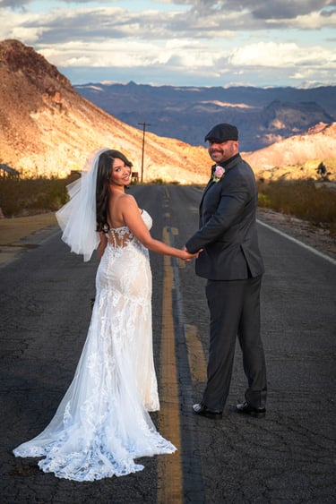 a bride and groom holding hands on a road