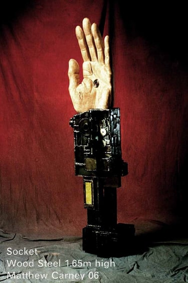 a carved wooden hand with a camera embedded in the palm on a steel armature with circuit boards