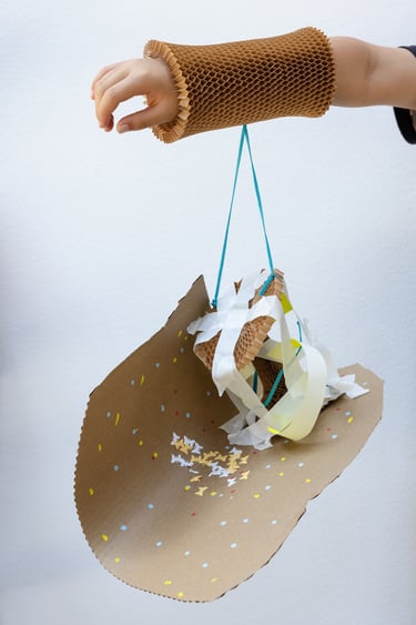 An outstretched arm with a cardboard artwork hanging off it.