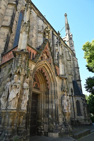 Gothic architecture of a cathedral entrance featuring stone saint statues and ornate carvings.