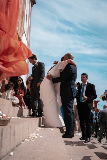 Bride stepping out of the ceremony venue surrounded by cheering guests
