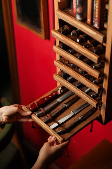 Hand opening a custom wooden knife rack storage drawer holding vintage steak knives.