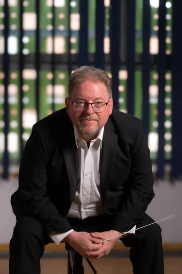 Robert in a suit and tie is sitting on a chair