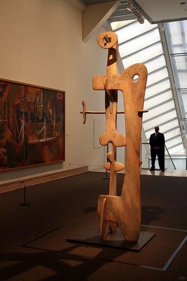 Large wooden Isamu Noguchi sculpture displayed in a museum space with warm natural material and orga