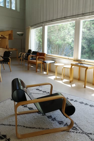Alvar Aalto Studio interior with wooden armchairs, natural light and a large window facing greenery