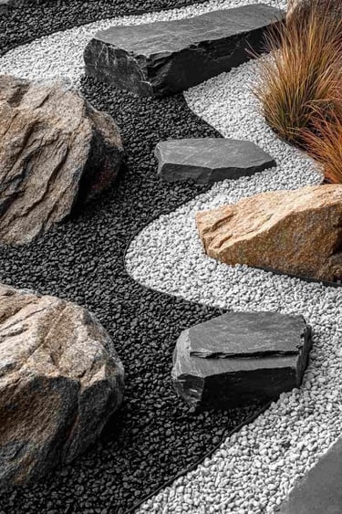 Natural stone garden design with black and white gravel, stepping stones, large rocks and ornamental