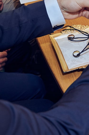 Der Trauzeuge legt vor der Trauung die Eheringe an den Halsketten auf einen Teller.