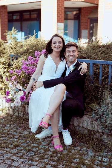 Die Braut sitzt auf den Knien des Bräutigams.