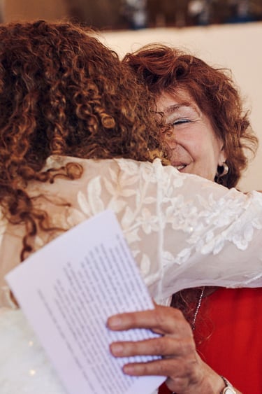 Die Mutter des Bräutigams umarmt die Braut.