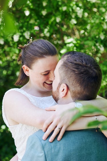 Bride hugging groom and touching his nose with hers.