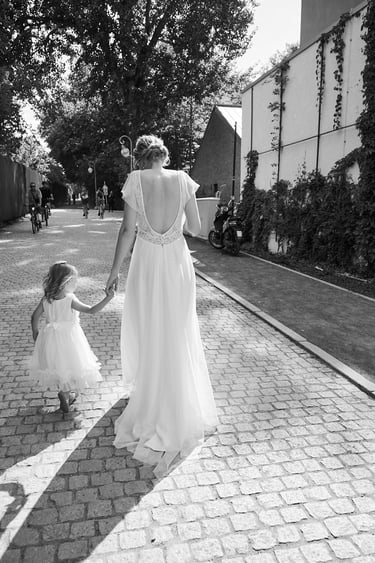 Bride walking with flower girl on a cobbled street.
