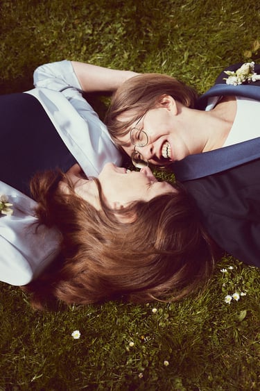 Two happy brides lying on the grass.