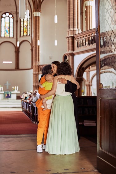 Newlywed lesbian couple hugging the pastor after the ceremony.