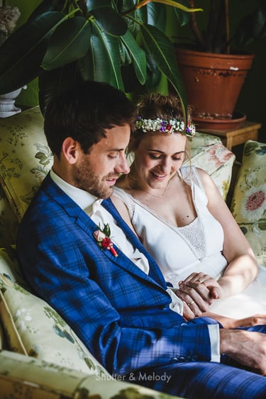 Bride and groom sitting on a couch and admiring their wedding bands.