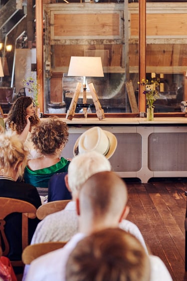 Braut und Bräutigam sehen ihre Mutter in einem roten Kleid an und sprechen.