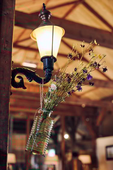 Vase with flowers handing from a wall lamp.