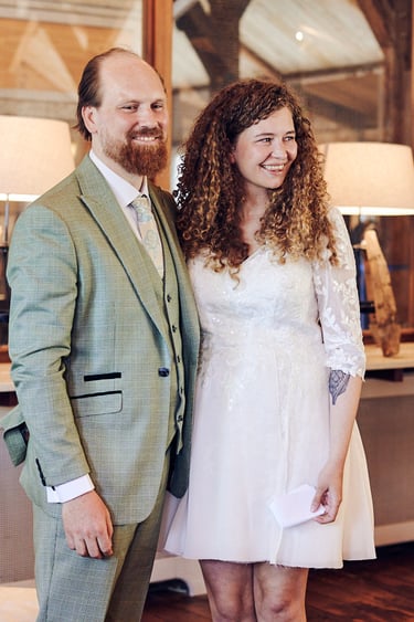 Braut und Bräutigam halten sich an den Händen und lächeln während der standesamtlichen Trauung.