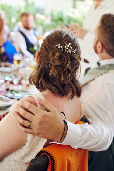 Groom embracing bride while they are sitting. 