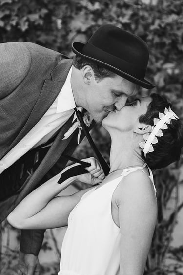 Bride pulling groom by the tie and kissing him.