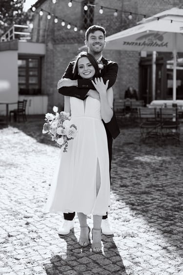 Groom hugging bride from behind.