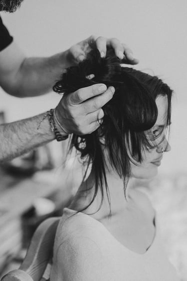 Ein Friseur stylt die Haare einer Braut.