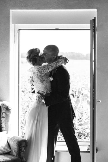 Wedding couple hugging in a window in the countryside.
