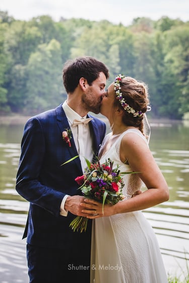 Bride and groom kissing next to a lake.