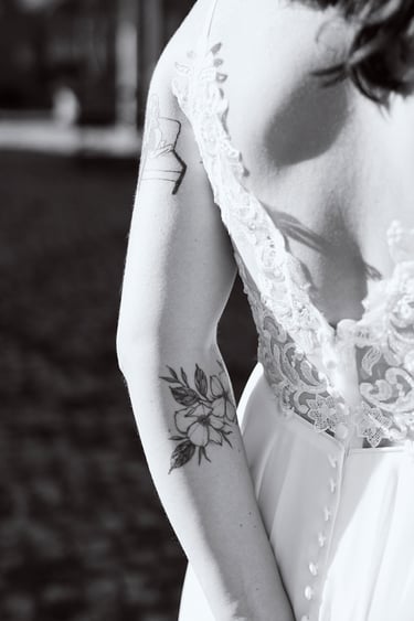 Der Arm der Braut mit einer Tätowierung einer Blume.