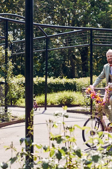 Braut und Bräutigam fahren auf einem Tandemfahrrad in einem Park.