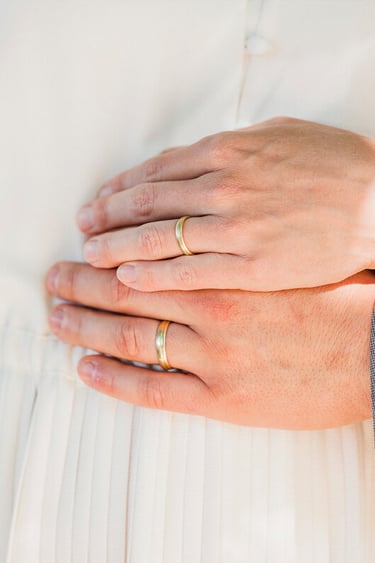 Hände von Braut und Bräutigam mit Eheringen.