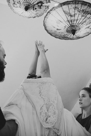 Friends helping bride put on her dress.