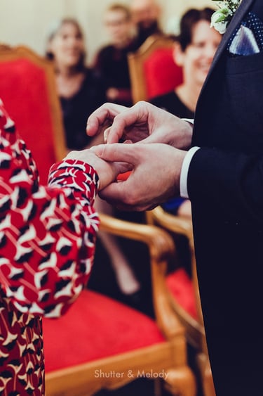 Groom putting a ring on the bride's finger.