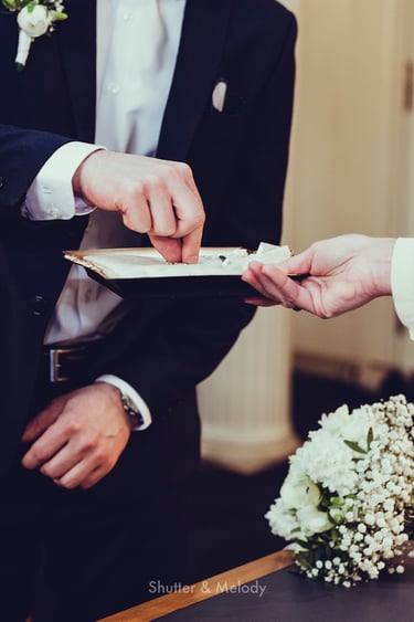Groom picking up wedding band from a tray during ceremony.