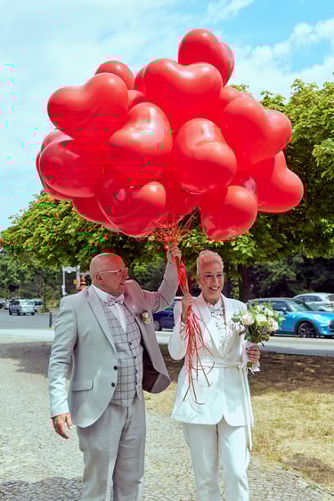 Braut und Bräutigam halten herzförmige Luftballons.