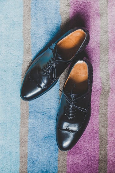Hochzeitsschuhe auf einem blau-lila gestreiften Teppich.