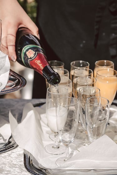 Waiter pouring sparkling wine into glasses.