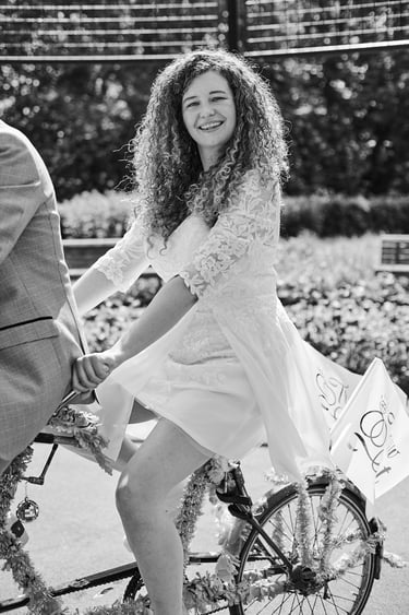 Smiling bride riding on a bicycle.