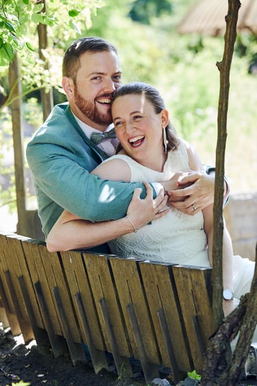 Couple laughing while sitting on a bench and hugging.