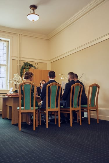 Two grooms signing documents with their witnesses in a civil registry.