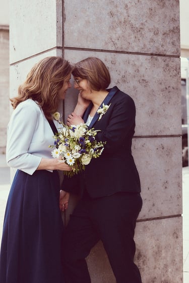 Zwei verliebte Ehefrauen, die sich an eine Säule lehnen.