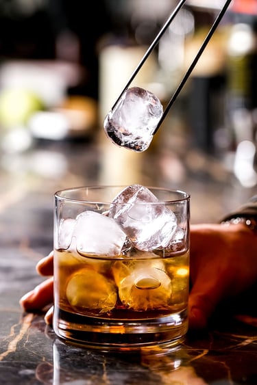 Μπάρμαν προσθέτει πάγο σε ποτήρι με ποτό