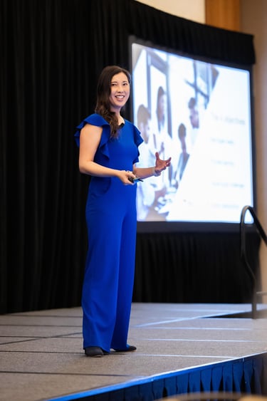 Unleashing Radiance speaker presenting confidently on stage in blue jumpsuit.