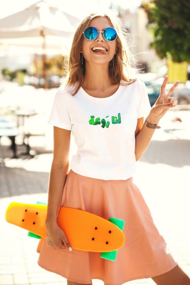 Model showcasing a handmade Fishberry statement tee with 3D lettering, smiling with a skateboard