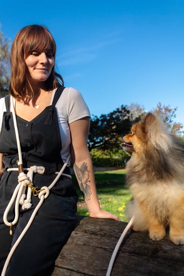 a woman in overalls and overalls sitting on a bench with a dog