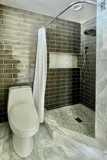 A bathroom with marble floor tile, and full height grey subway wall tile.