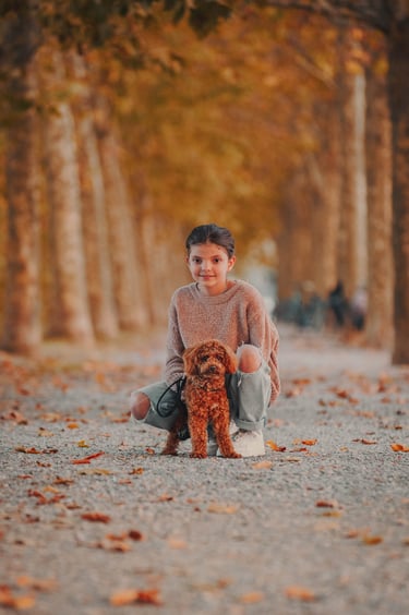 bambina col proprio cane marrone sulle mura di Lucca in autunno