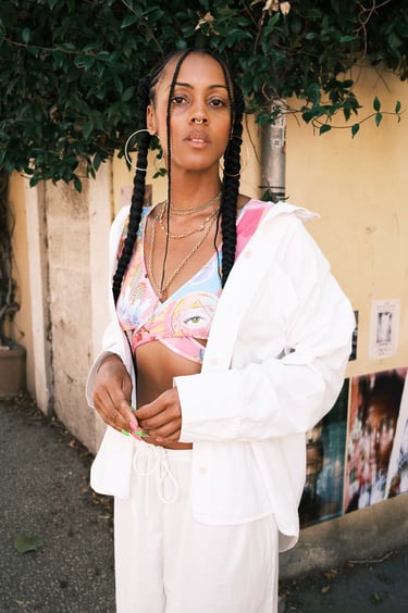 portrait d'une femme noire avec brassière colorée et pantalon ample blanc